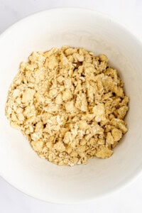 A bowl filled with a dry, crumbly mixture, likely a blend of oats, flour, and butter, commonly used for a crumble topping in baking.