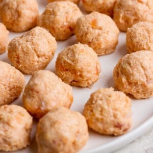 A plate of uncooked salmon balls arranged in rows on a white surface.