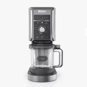 A Ninja kitchen appliance with a digital display and control knob sits on a white background, ready to craft your creami protein ice cream. It features a clear mixing container with a handle at the base for easy maneuvering.