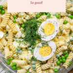 Deviled egg pasta salad with rotini, green peas, dill, and halved boiled eggs on top, served in a glass bowl. Text reads "Deviled Egg Pasta Salad - So good!.