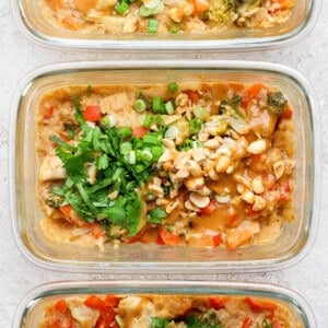 Three glass meal prep containers showcase a delicious peanut chicken stir-fry, garnished with chopped peanuts and cilantro.