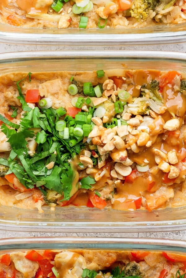 Three glass meal prep containers showcase a delicious peanut chicken stir-fry, garnished with chopped peanuts and cilantro.