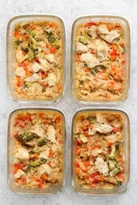 Four glass containers filled with a delightful mixed dish of rice, broccoli, red bell peppers, and chunks of peanut chicken.