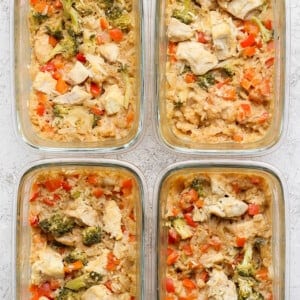 Four glass containers filled with a delightful mixed dish of rice, broccoli, red bell peppers, and chunks of peanut chicken.