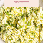 A bowl of cottage cheese egg salad garnished with chopped green onions and dill, with a gold spoon on the side. Text overlay reads “Cottage Cheese Egg Salad, High-protein idea!”.