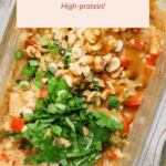 Glass container filled with meal-prep peanut chicken, topped with chopped peanuts, green onions, cilantro, and diced red peppers. Text label highlights "High-protein!".