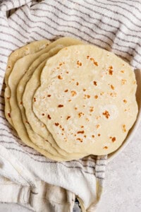 A stack of homemade flatbreads resting on a striped kitchen towel.