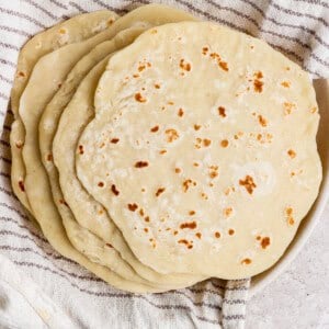 A stack of homemade flatbreads resting on a striped kitchen towel.