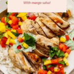 A plate of sliced cilantro lime chicken served over rice with colorful mango salsa and a drizzle of green sauce, garnished with cilantro.