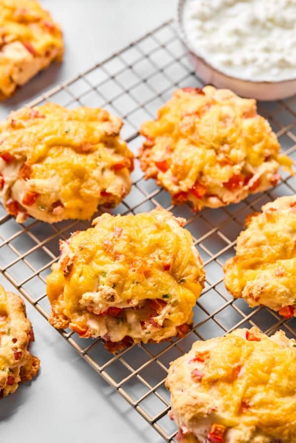 Cheddar and red pepper scones cooling on a wire rack, with a bowl of cottage cheese in the background.