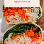 A chicken Caesar spread wrap cut in half, showing layers of shredded chicken, carrots, and leafy greens in a tortilla, stacked on a white plate.
