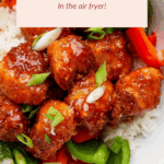 A bowl of sweet and sour chicken on white rice, garnished with sliced green onions and served with red and green bell peppers. Text overlay promotes air fryer preparation.
